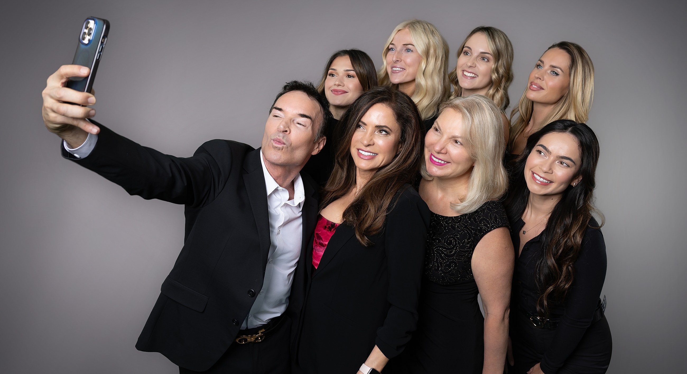 Group selfie with smiling individuals in formal attire.